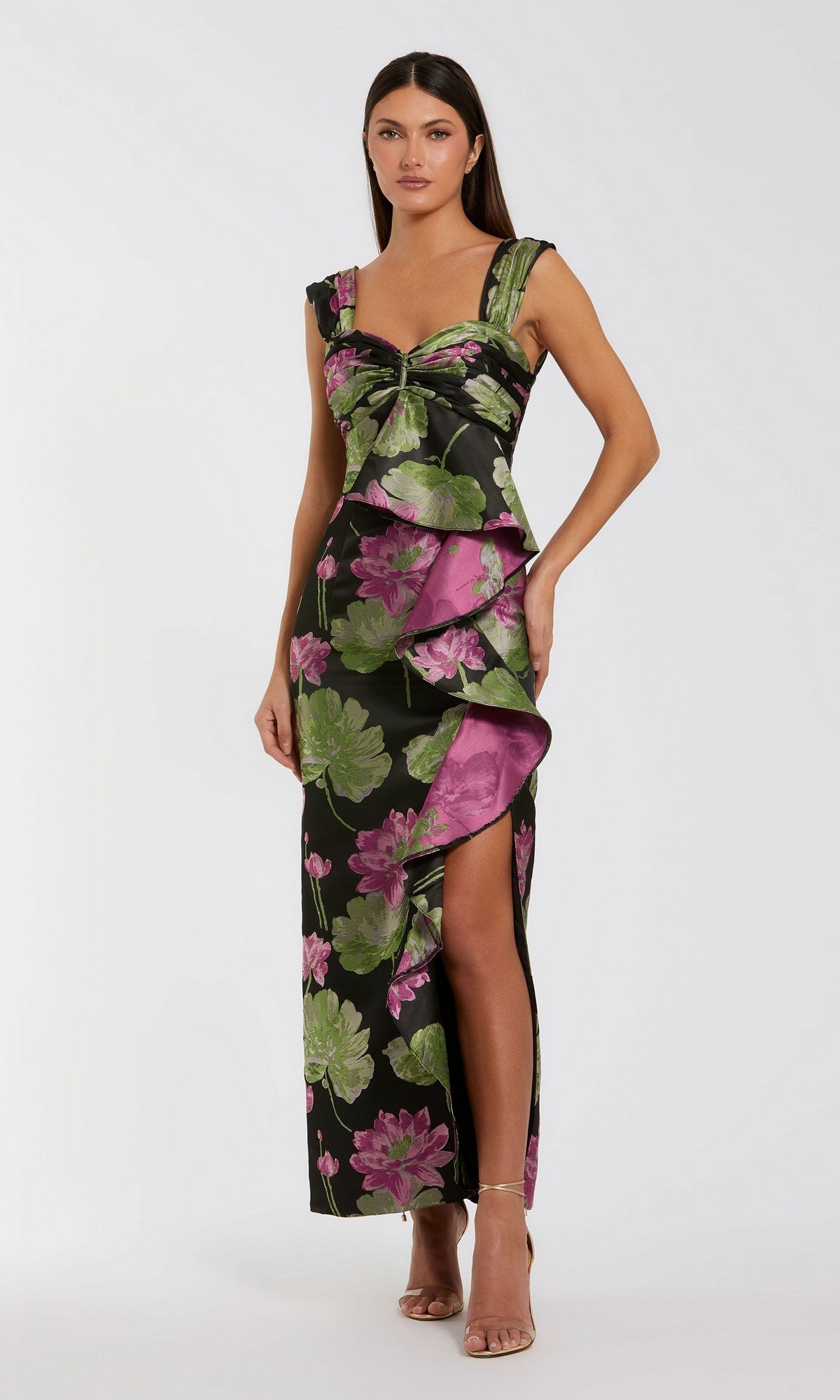 Wearing the Mac Duggal 37095 Long Formal Dress in Black Multi—a sleeveless gown adorned with pink and green floral prints, a sweetheart neckline, ruffle details, and a high side slit.